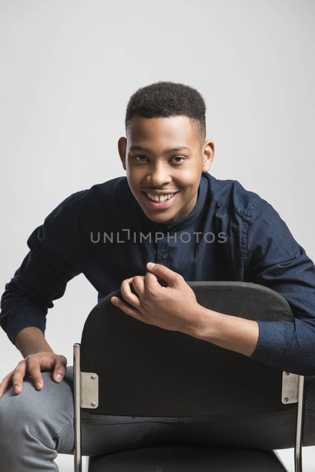 Portrait of handsome dark skinned male model smiling and wearing casual clothes against white background