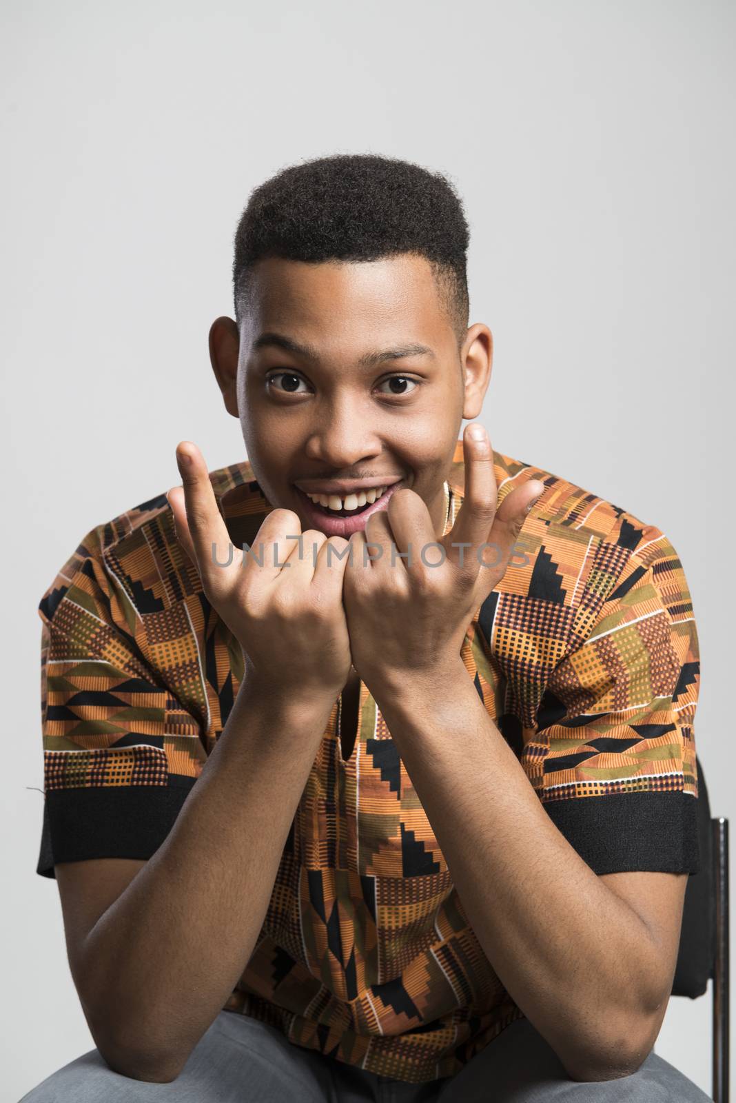 Portrait of handsome dark skinned male model smiling and wearing traditionally African clothes against white background