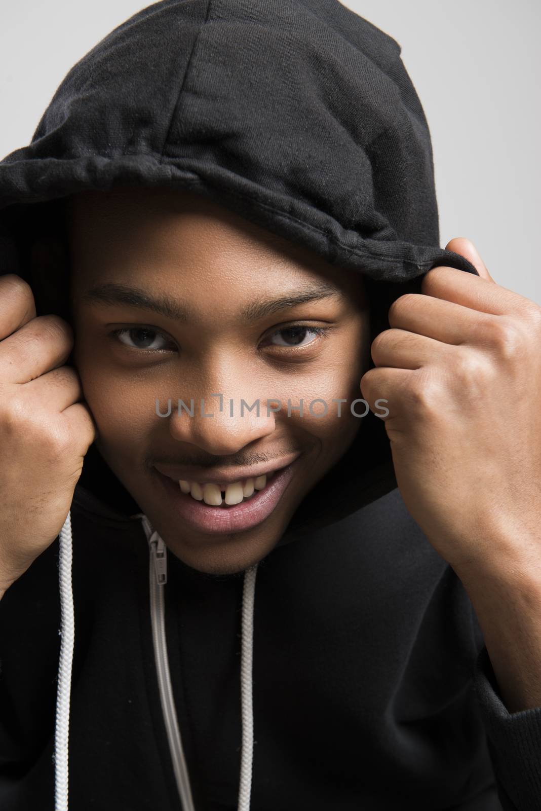 Portrait of handsome dark skinned male model wearing black hooded jumper