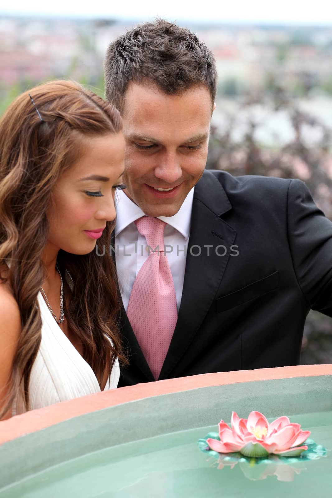 Wedding on the nature, bride and groom looking a water-lily flower