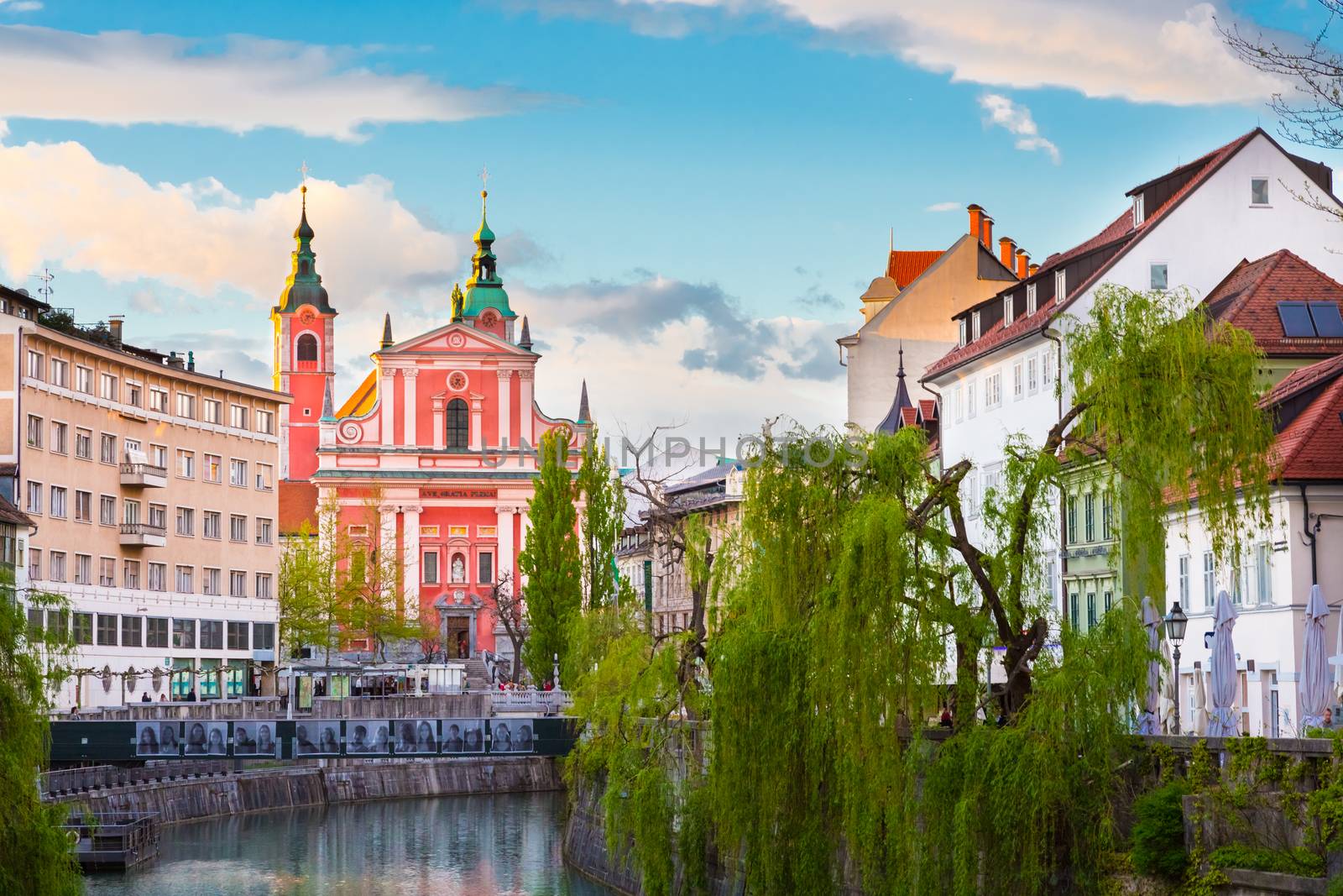 Romantic medieval Ljubljana's city center, capital of Slovenia, Europe. Night life on the banks of river Ljubljanica where many bars and restaurants take place. Franciscan Church in background