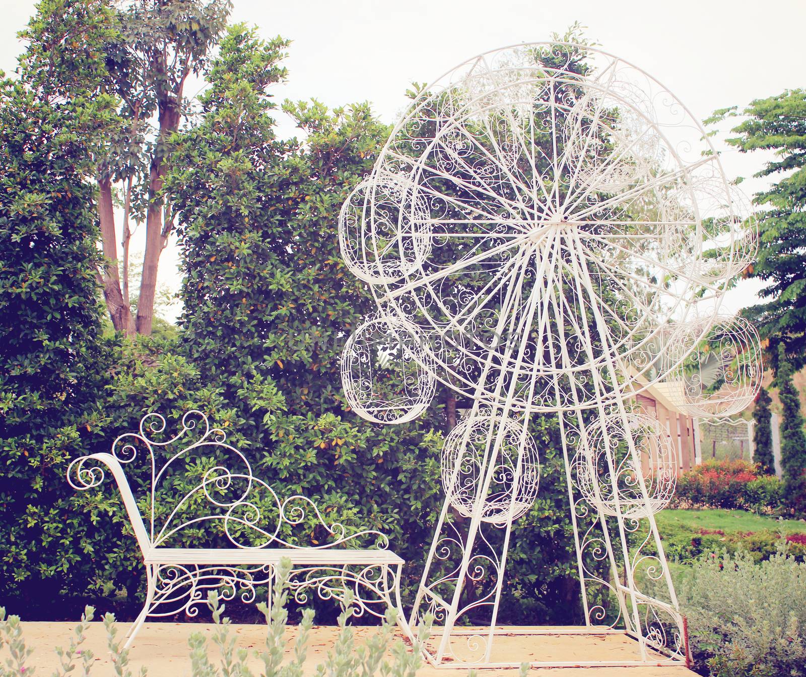White curved steel bench and ferris wheel in the garden, retro filter effect