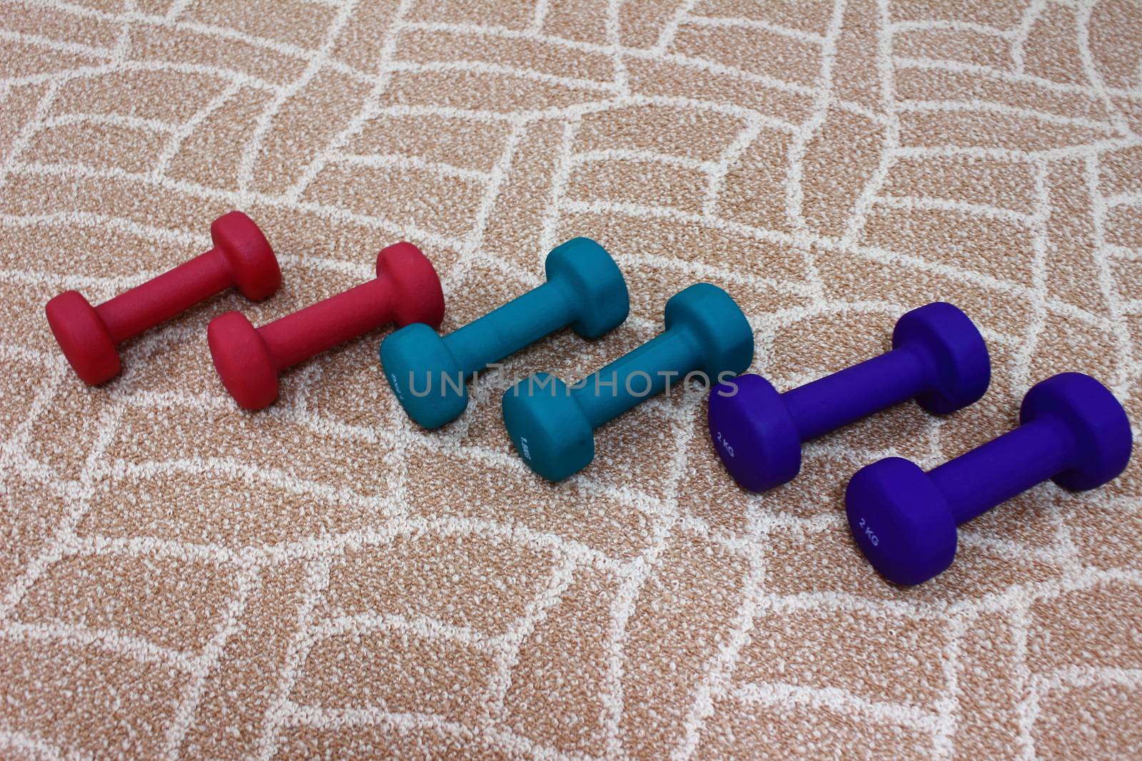 Red, green, blue dumbbells lie on the carpet for charging