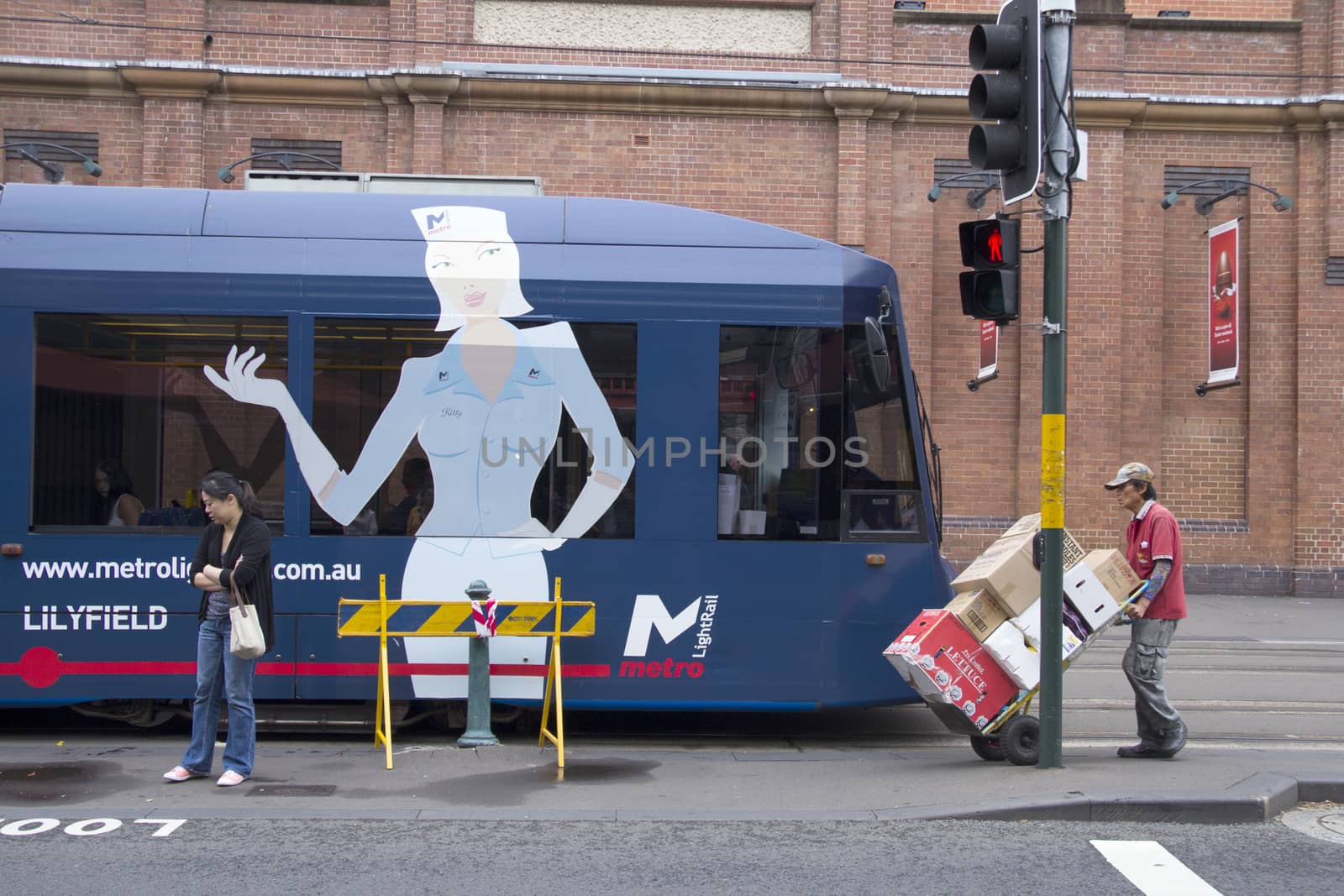 Sydney, Australia-March 15th 2013:: A porter wheels produce past a stationary tram in Haymarket. Haymarket is famous for Paddy's Market and Chinatown