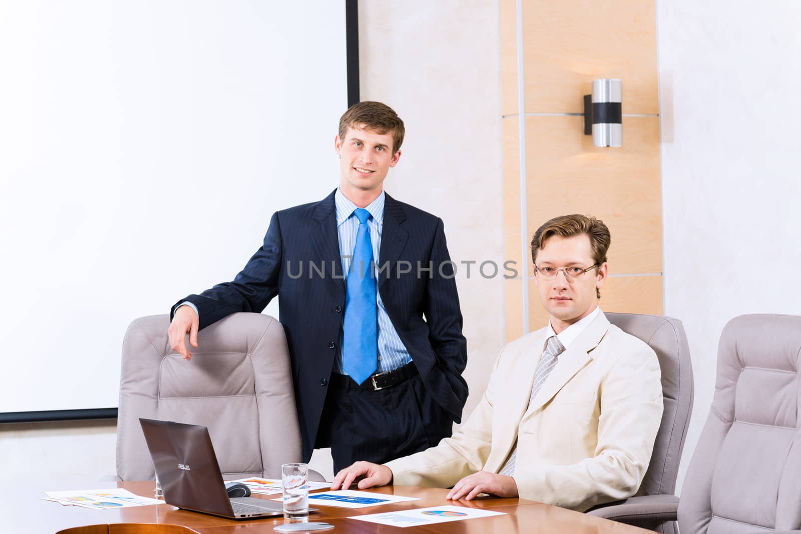 Business people talking, sitting at the table, watching the presentation on a laptop