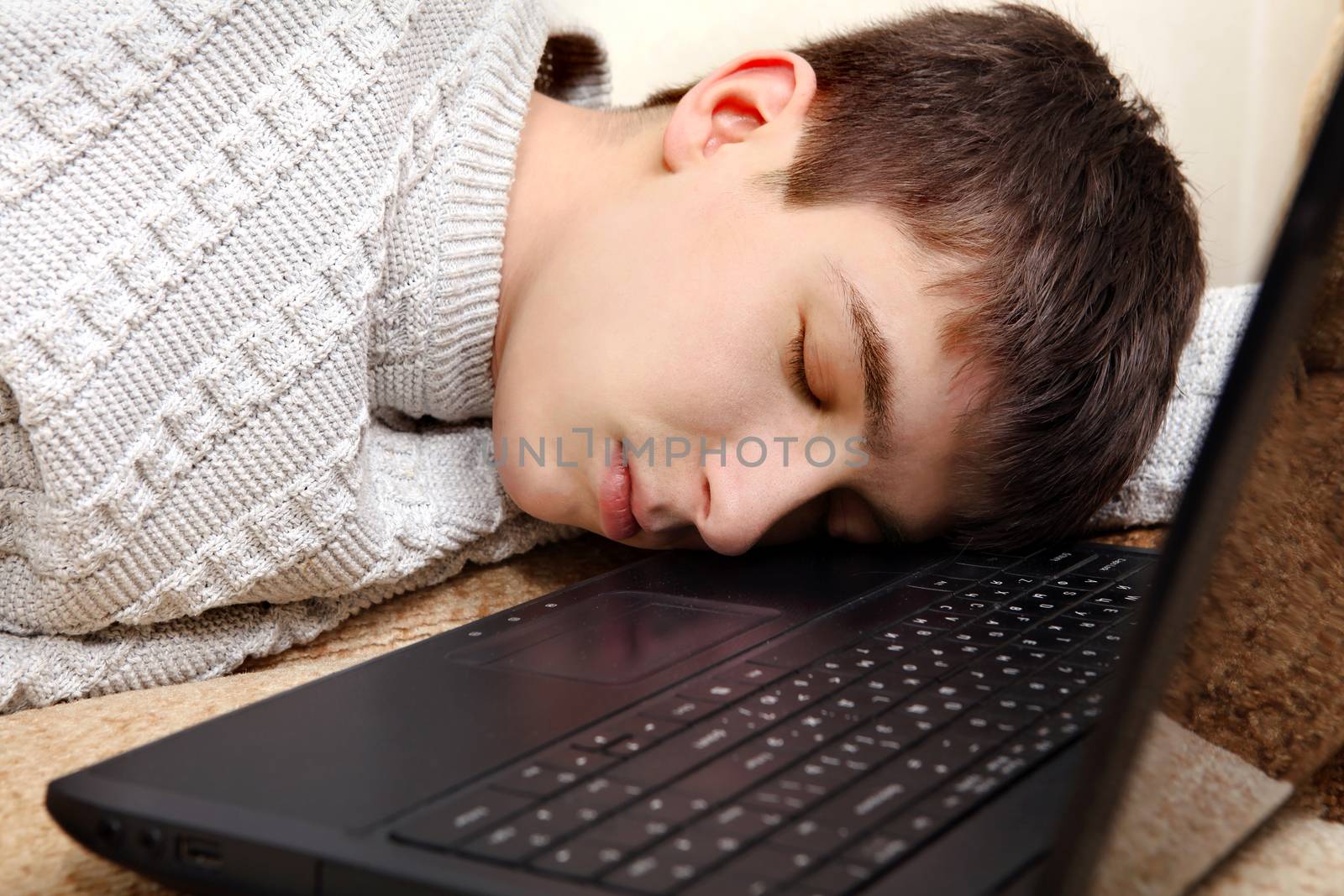 Tired Teenager sleeping with Laptop on Sofa at the Home