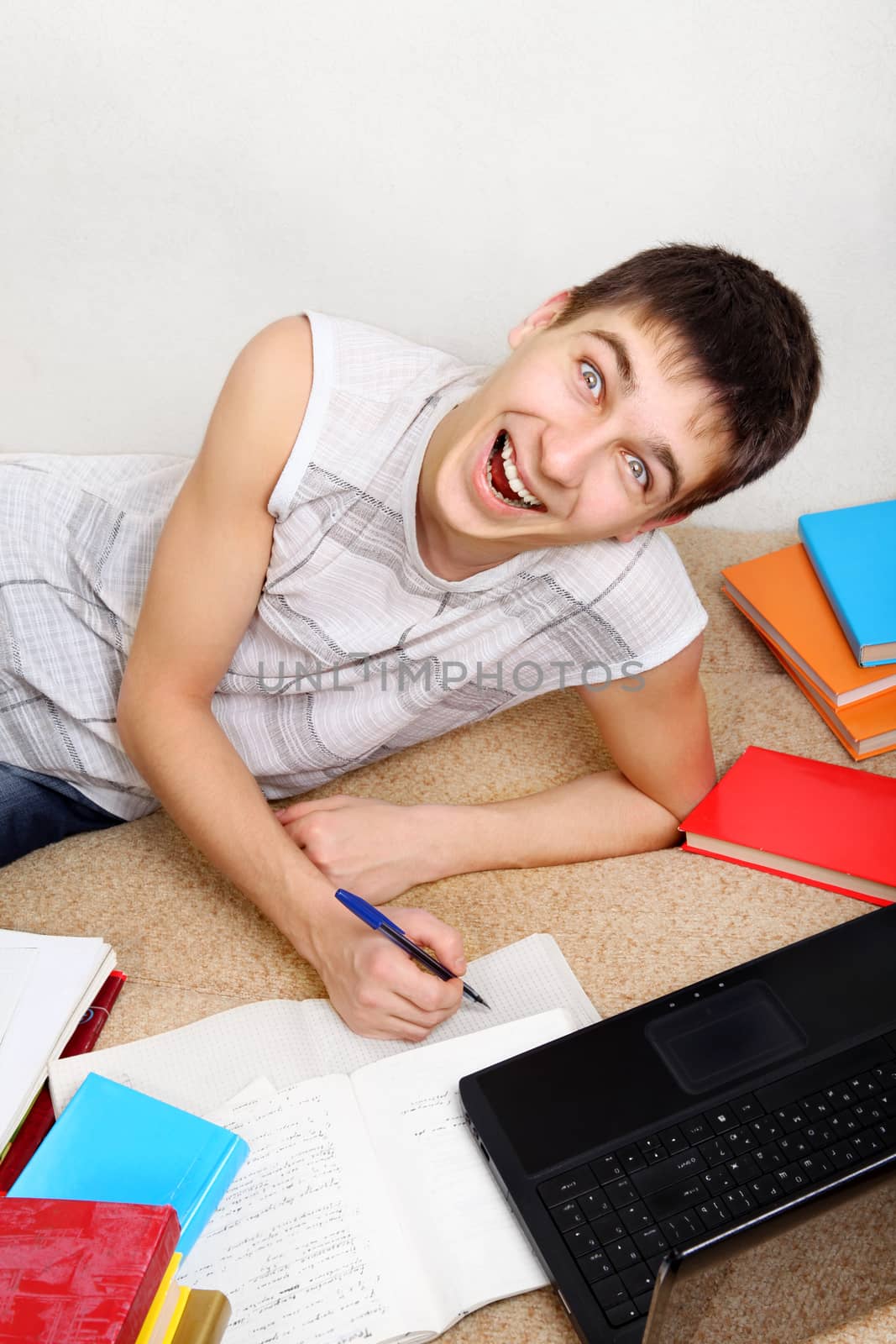 Cheerful Teenager doing Homework on the Sofa at the Home