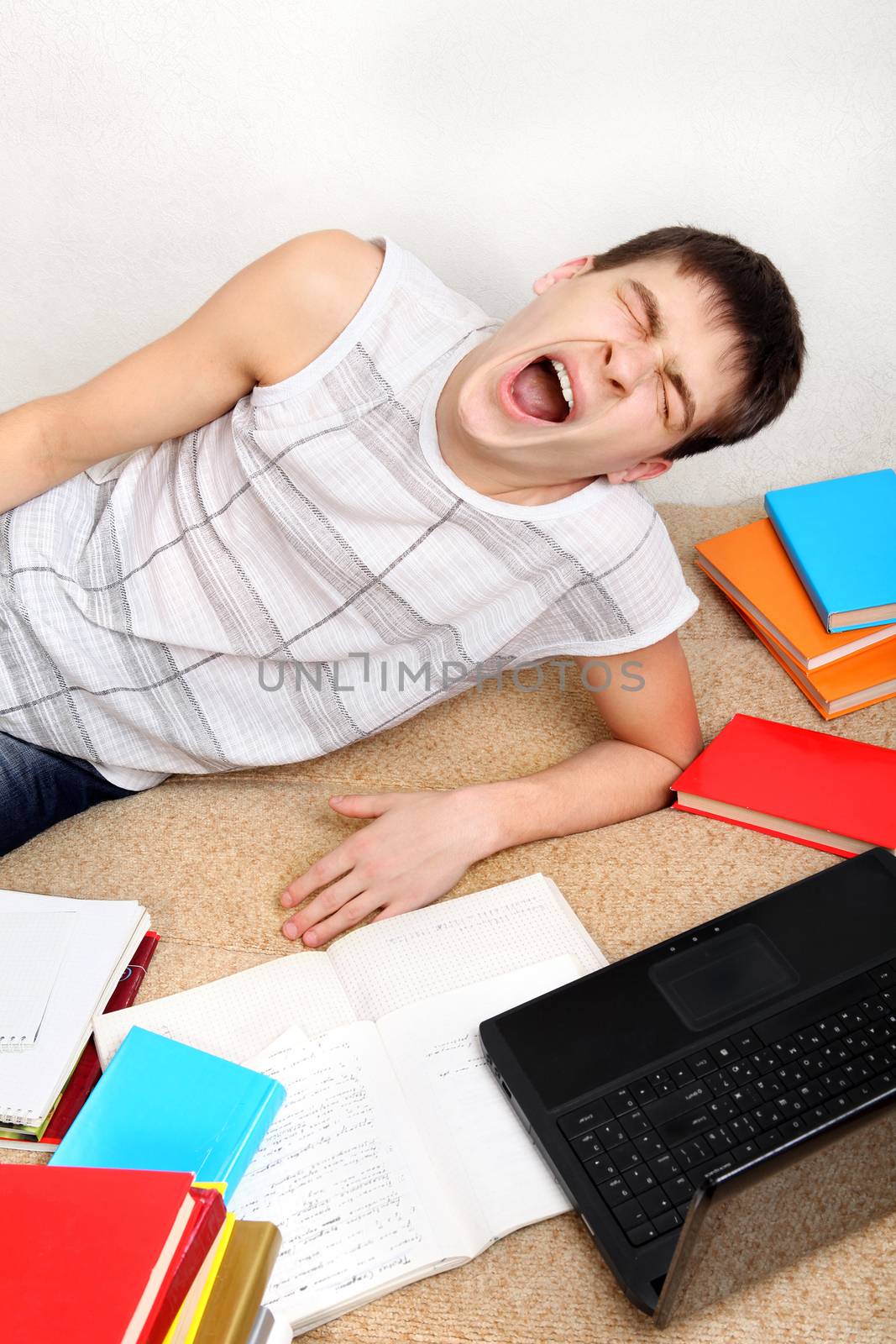 Tired Teenager Yawning on the Sofa with the Books at the Home