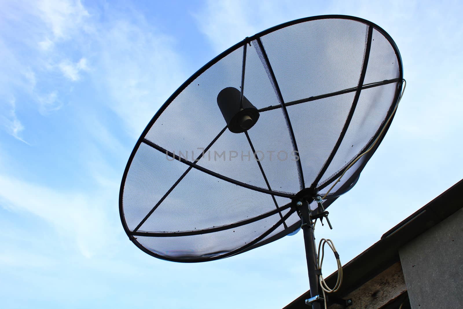 A satellite dish on the roof of the house with the blue sky.