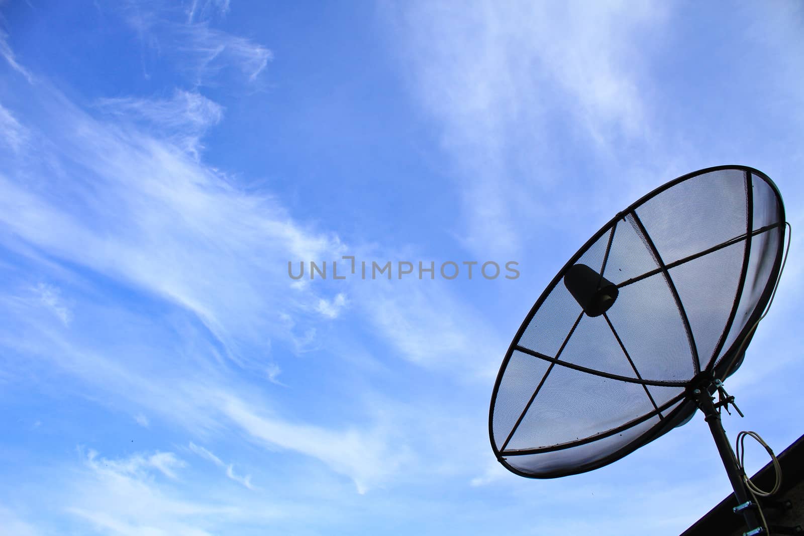 A satellite dish on the roof of the house with the blue sky.