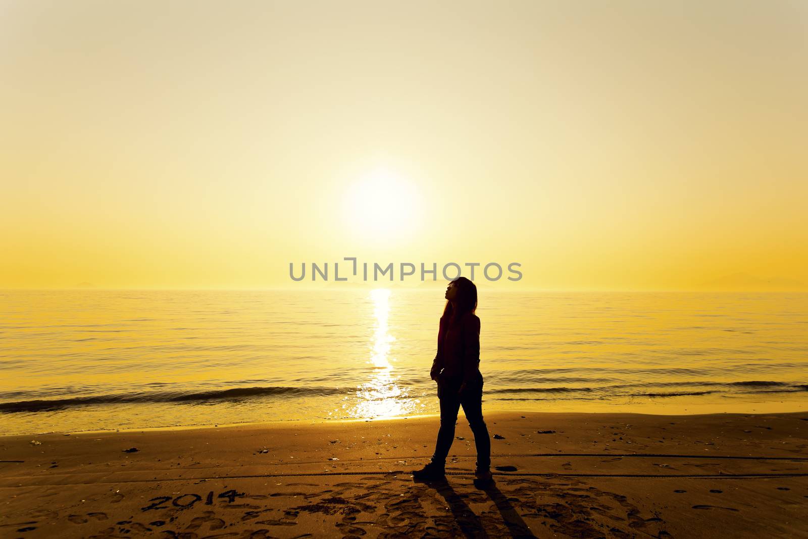 Young woman standing on beach under sunset 