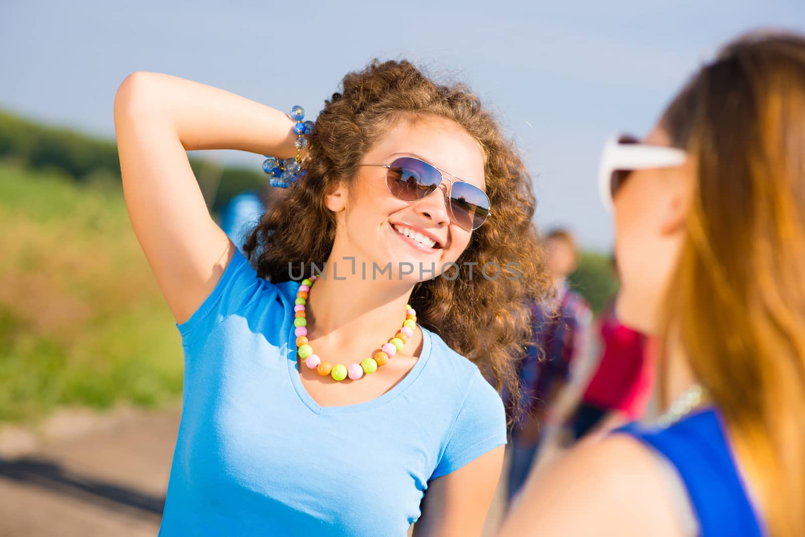 portrait of a stylish young woman on the background of young merry friends, spending time with friends