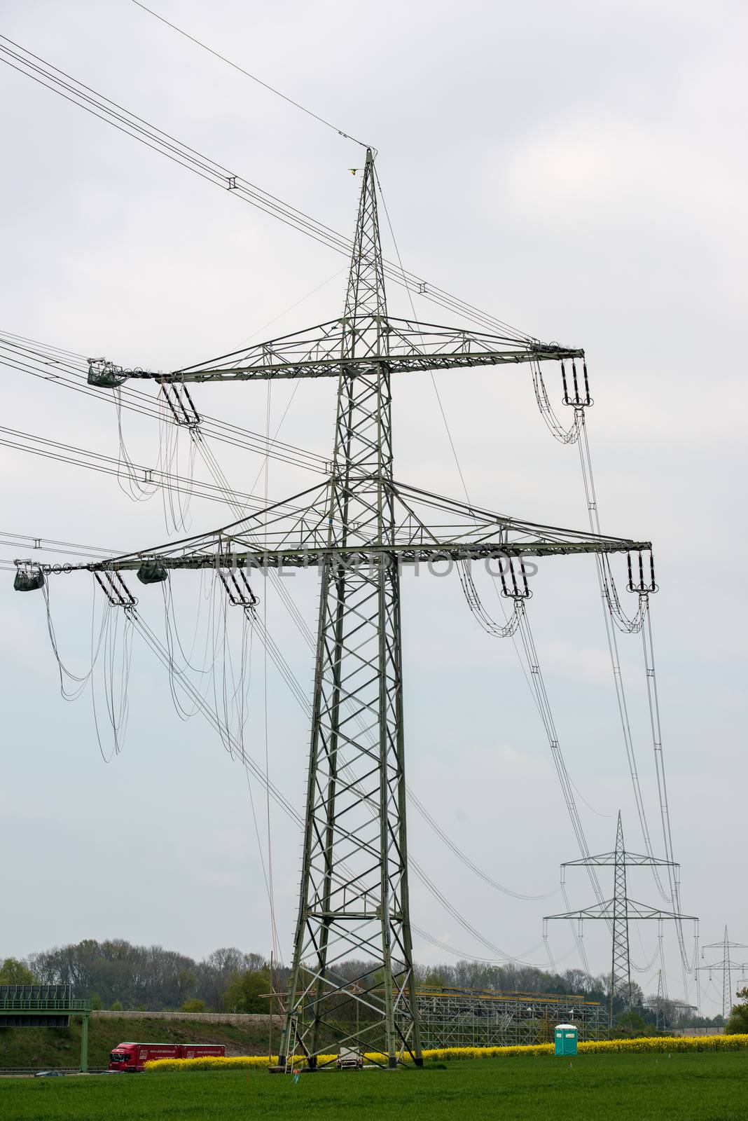 GUENZBURG, GERMANY - April 19, 2014: Construction works on high voltage power pole on April 19, 2014 near Guenzburg, Germany. The extended power lines are necessary due to increased power consumption by Legoland and other companies settling at Guenzburg. Since the power lines cross the Autobahn (highway), complex safety measures are in place.