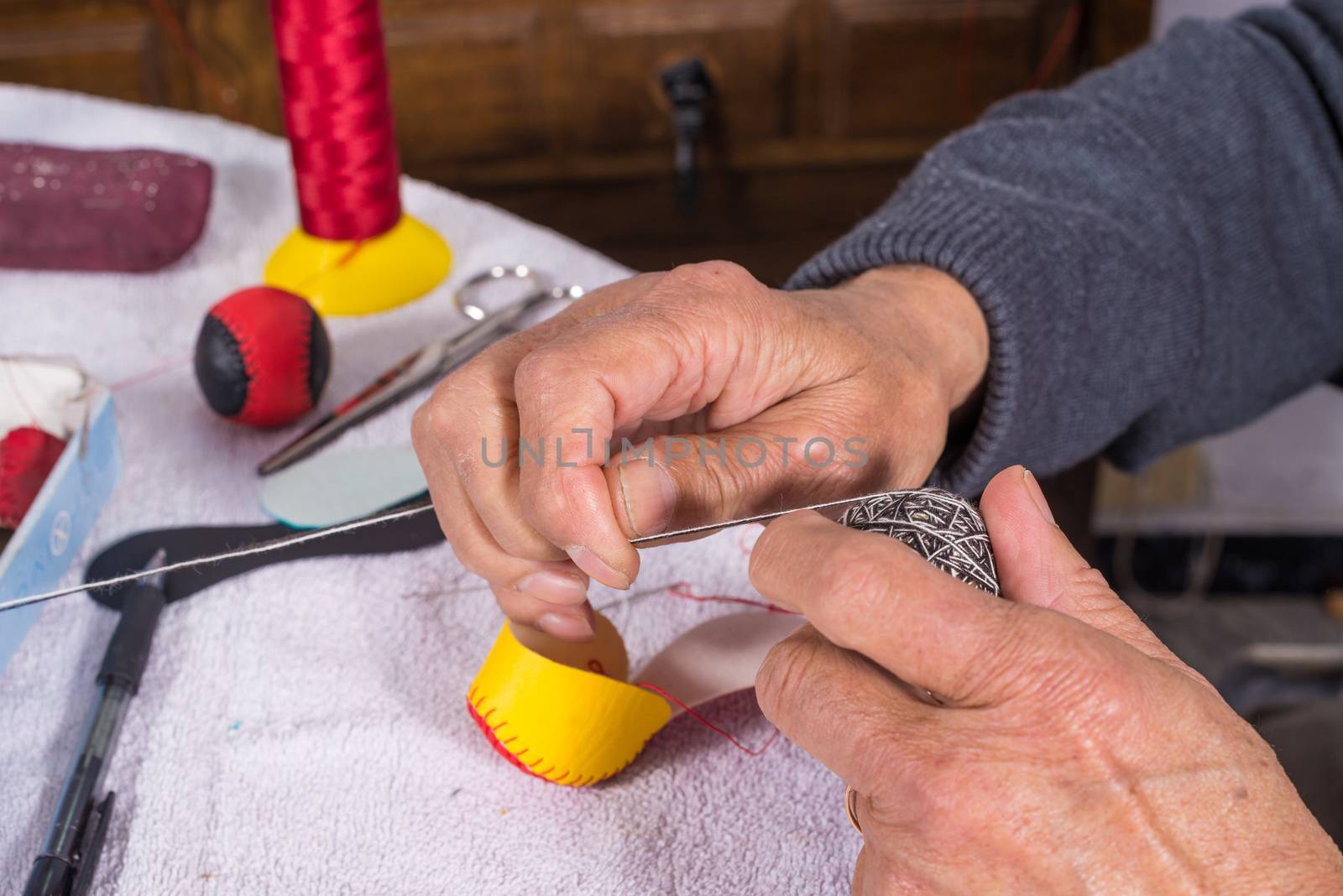 Old male hands sewing traditional jai alai balls