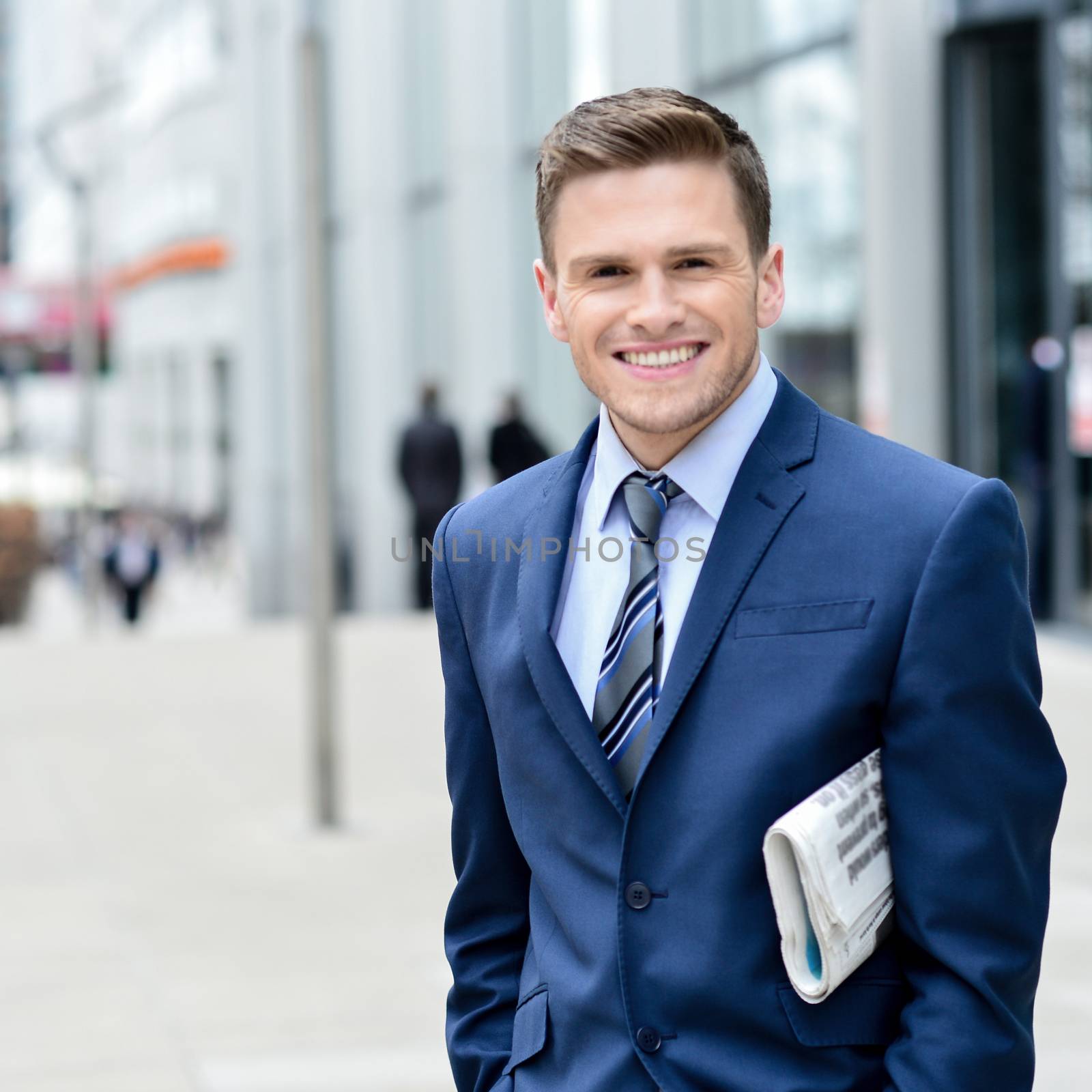 Smiling satisfied businessman holding news paper at outdoor