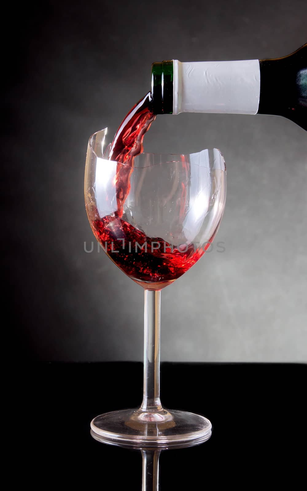 Pouring red vine into a broken glass by anderm
