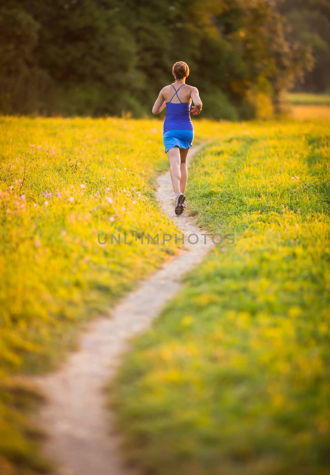 Young woman running outdoors on a lovely sunny summer evening by viktor_cap