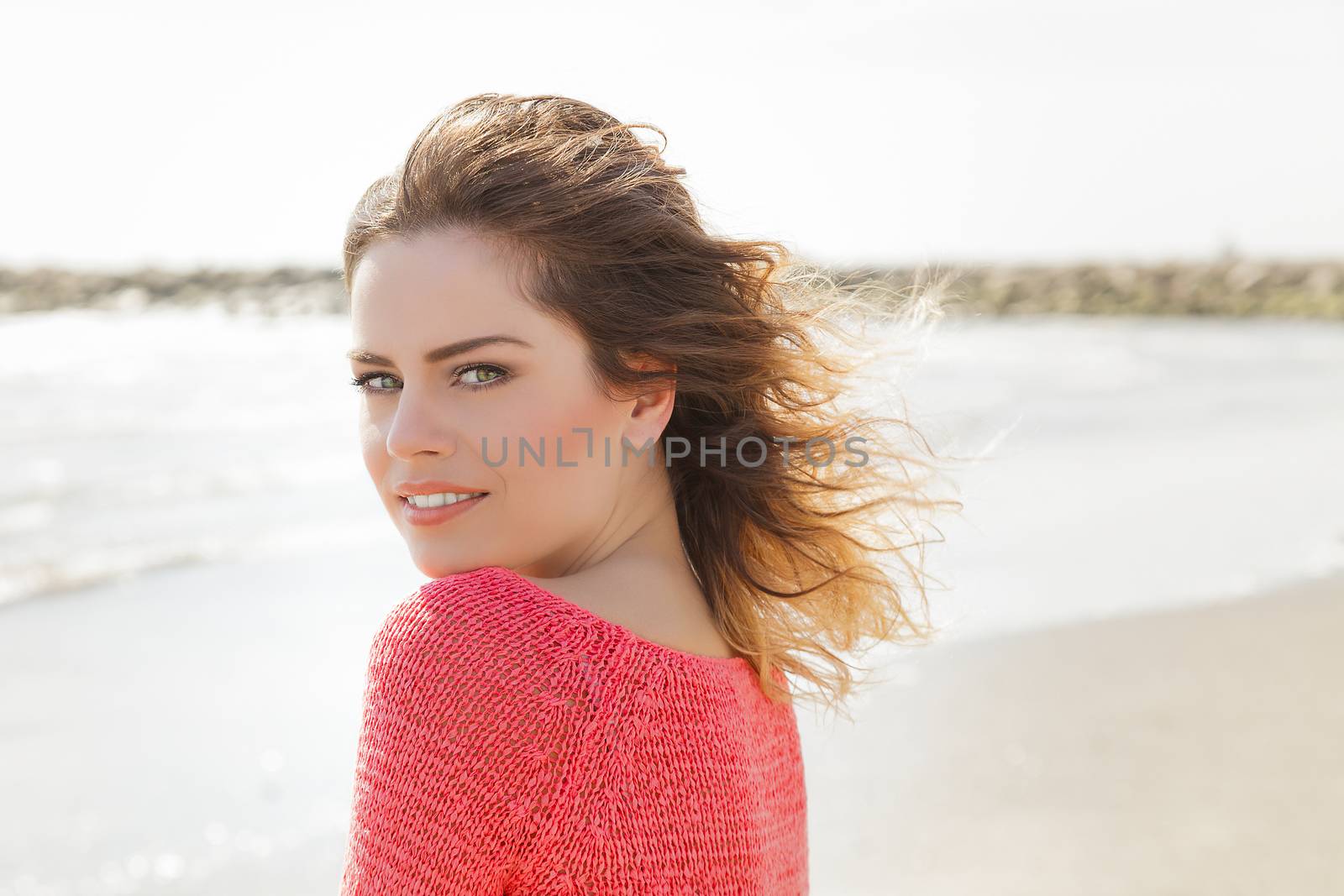 Beautiful green eyes woman smiling on a windy day at the seaside