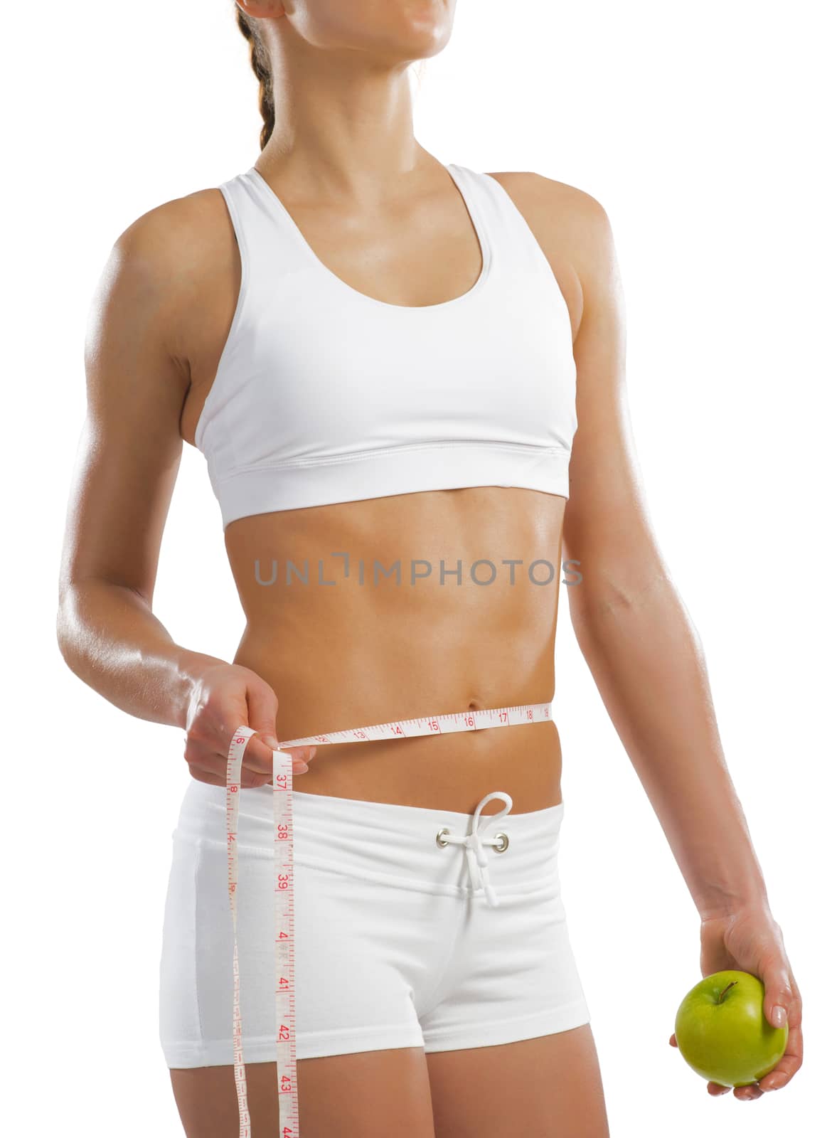 young athletic woman holding a green apple and measuring waist, isolated on white background