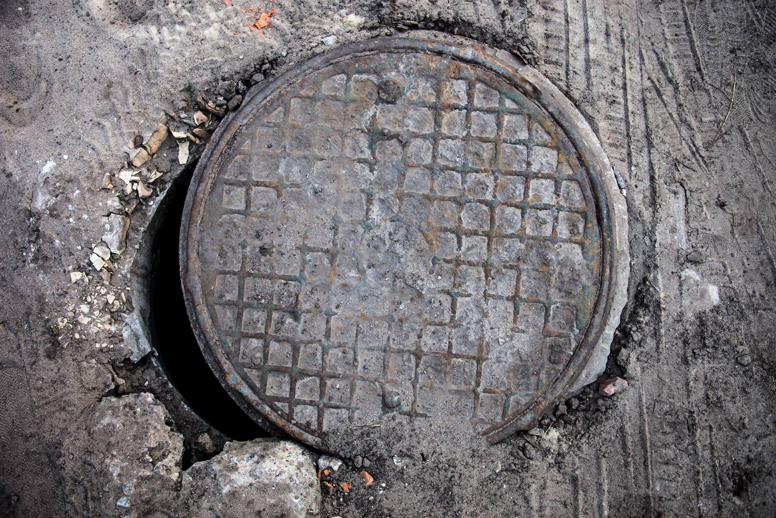 Open manhole with metal cover by rootstocks