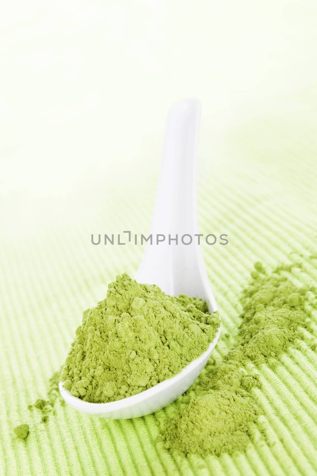 Detox. Wheatgrass powder on white spoon on green background. Alternative medicine. 