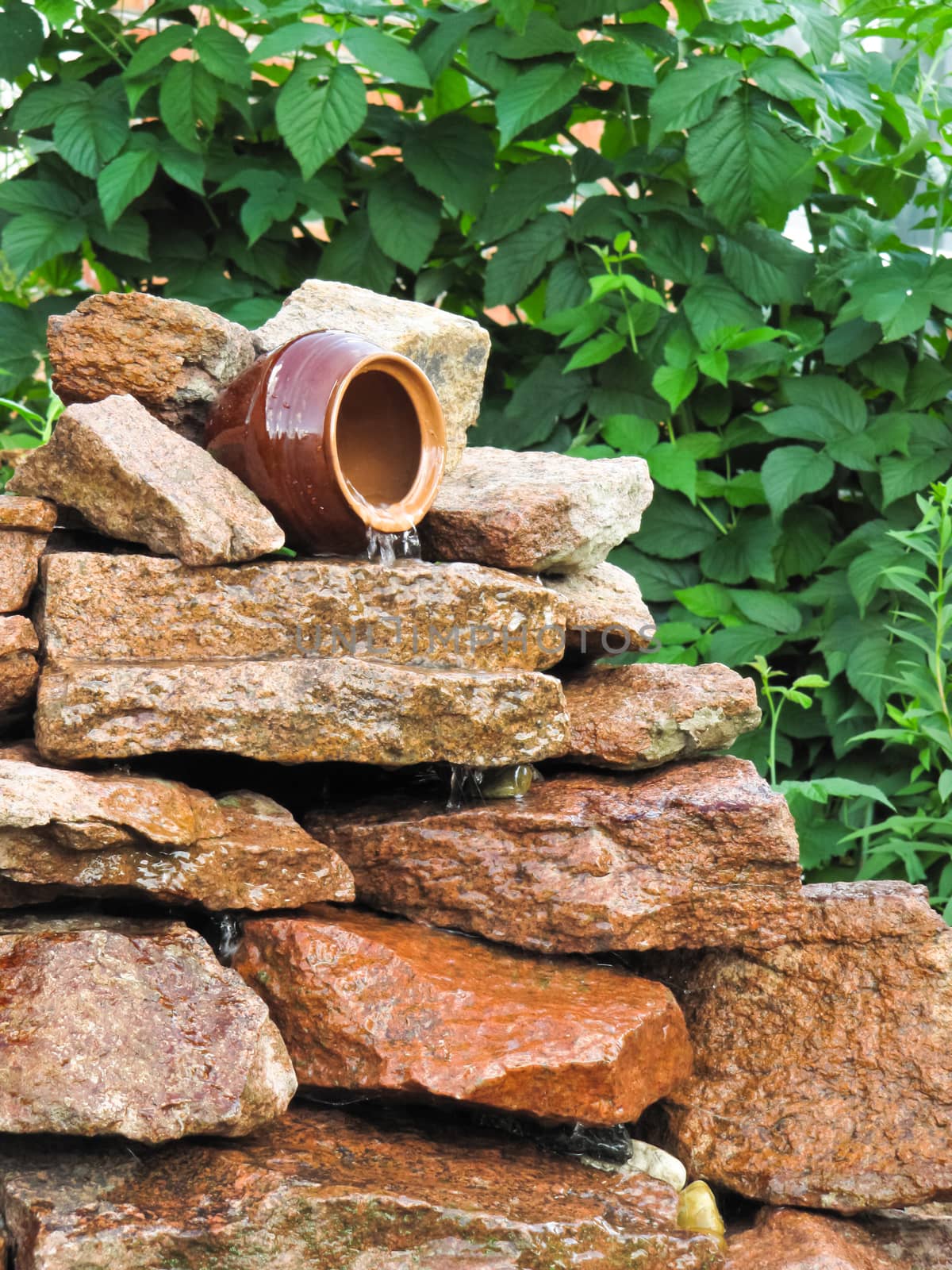 small waterfall of stones and a pot in the garden