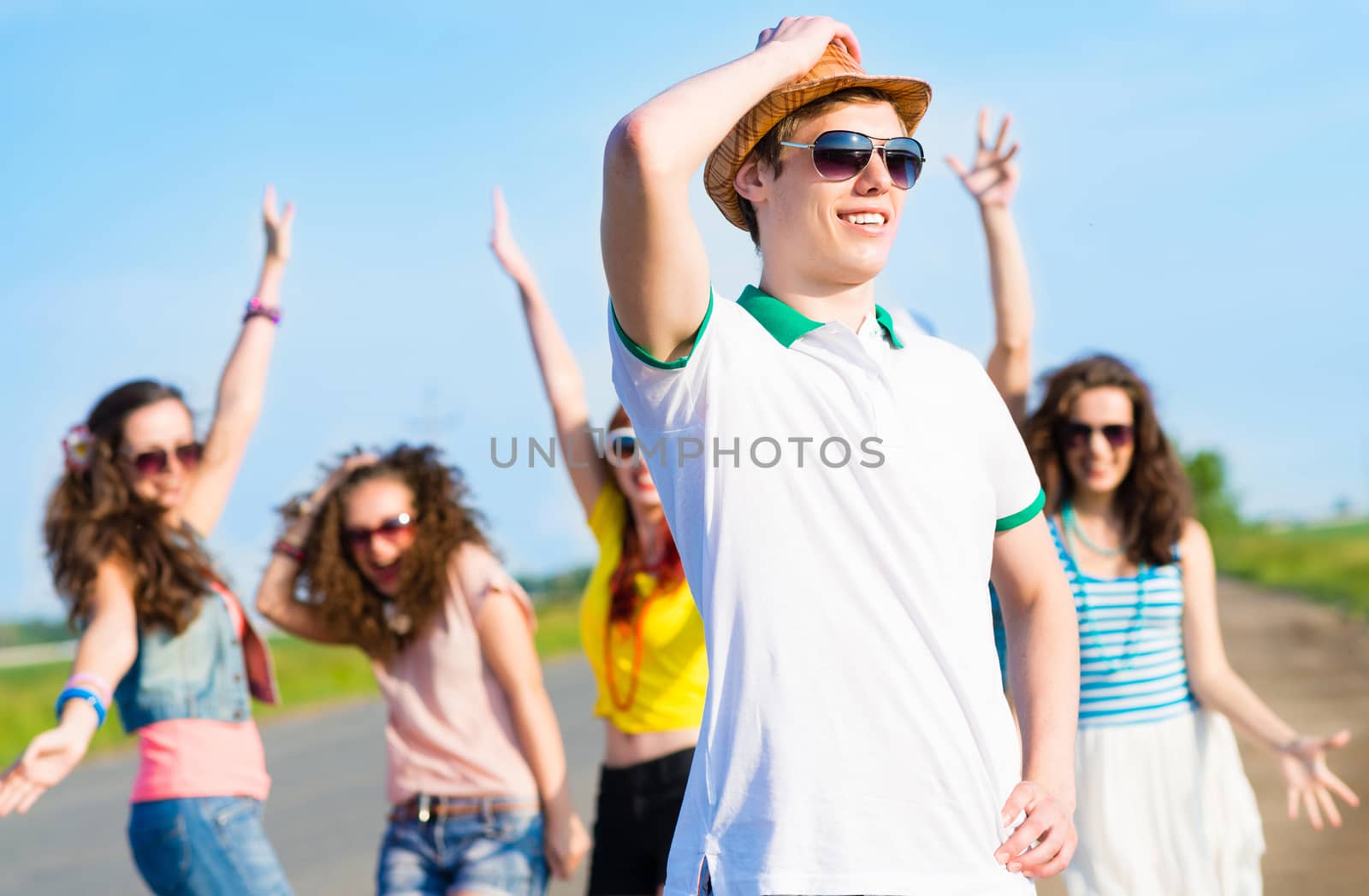 young man in sunglasses, a hat holds a hand on a background of blue sky and friends