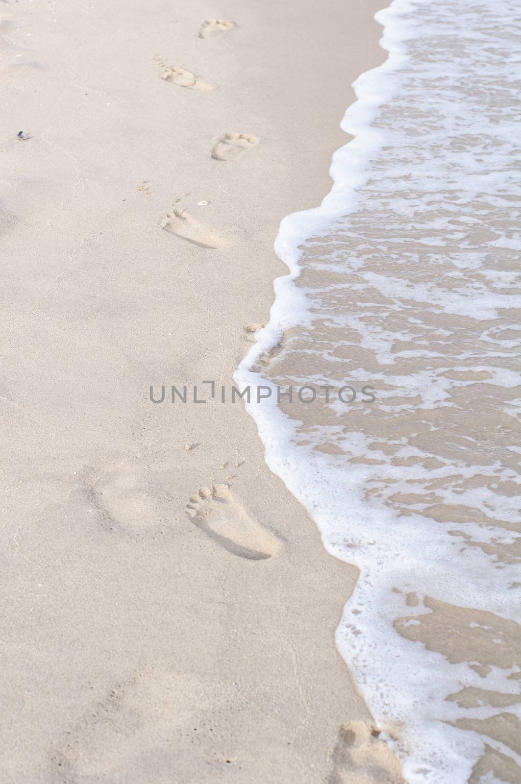 Footprints in wet sand of beach  by Sorapop