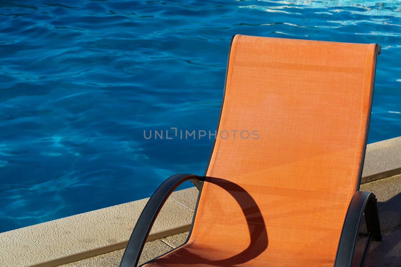 Chaise lounge around swimming pool at a sunny day