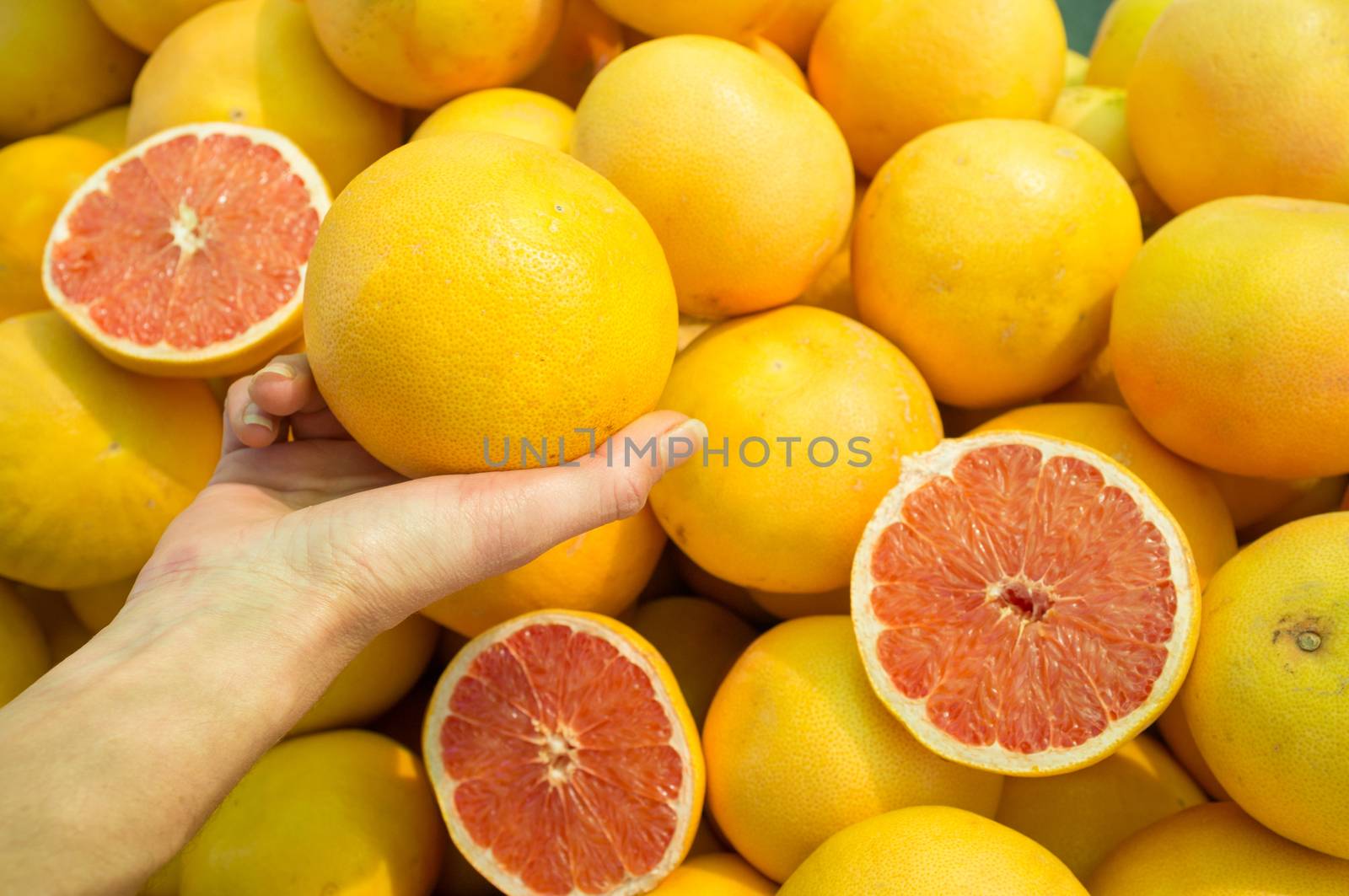 Female hand choosing grapefruit on  a street market stall