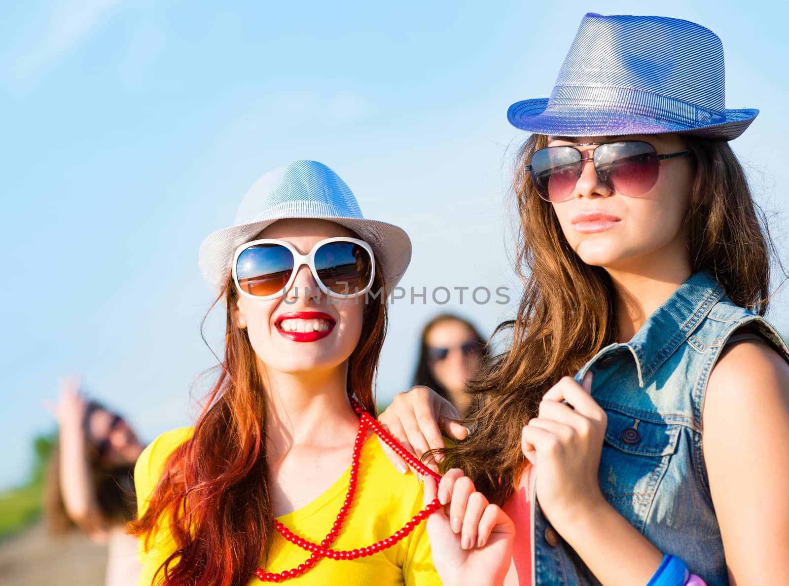 Two young girlfriends having fun on the background of blue sky and friends