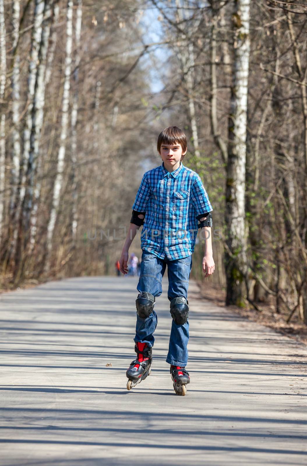 Kid skating on rollerblades in spring park