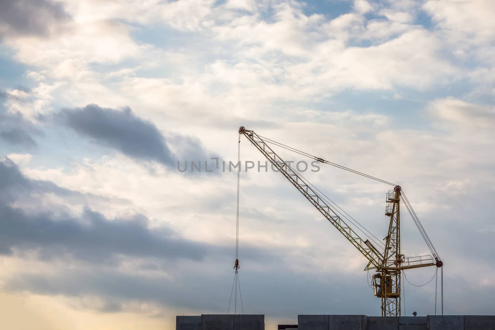 Construction crane on cloudy sky background