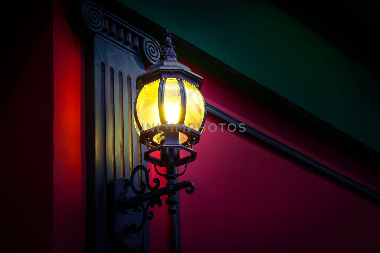 Vintage street lamp at the evening on red wall background