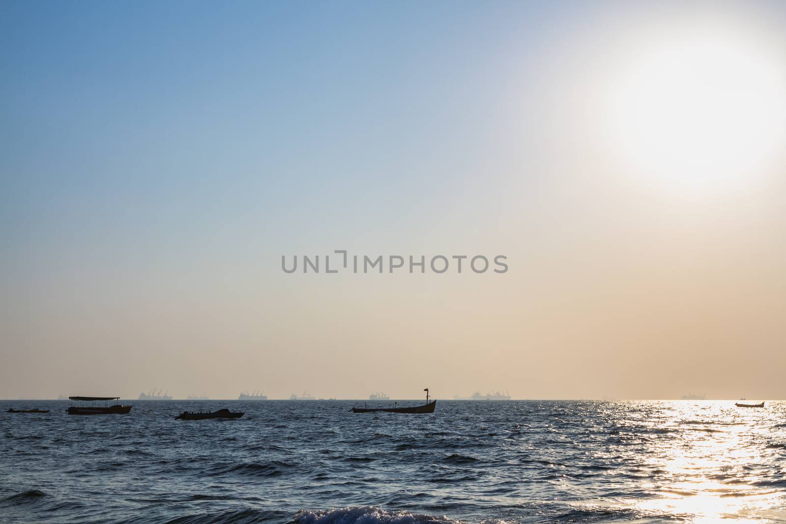 Fishermans boats at Arabian sea. Cargo ships on the background