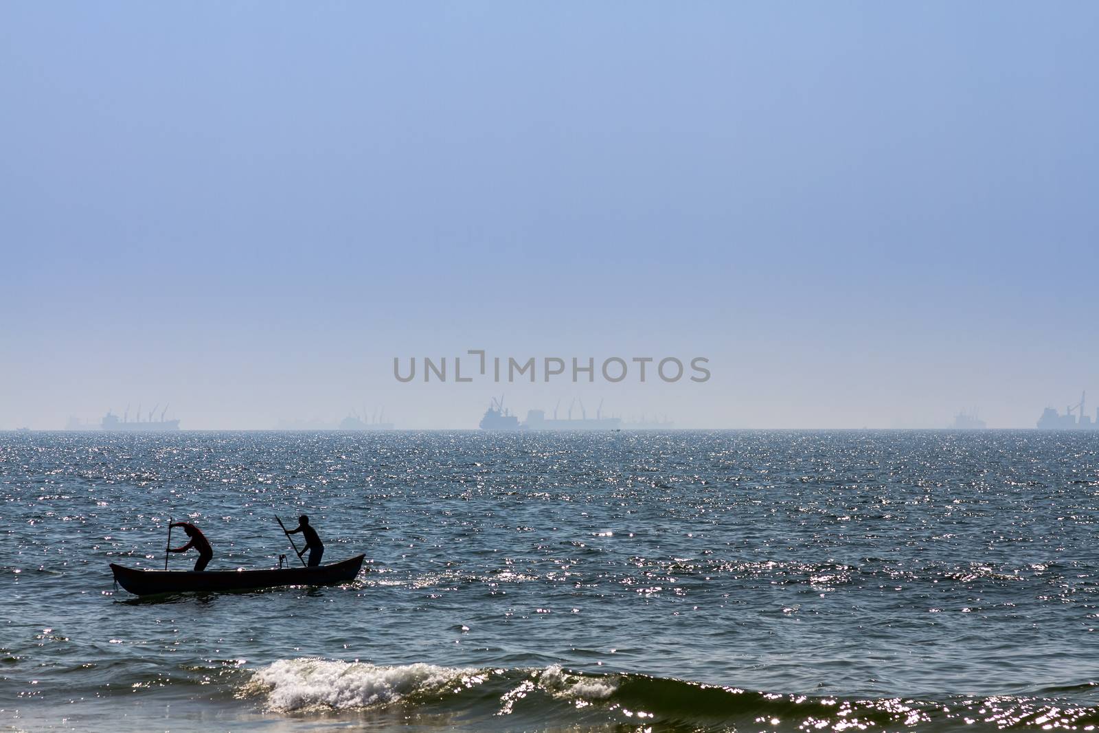 Boat with fishermans at Arabian sea. Cargo ship on the background