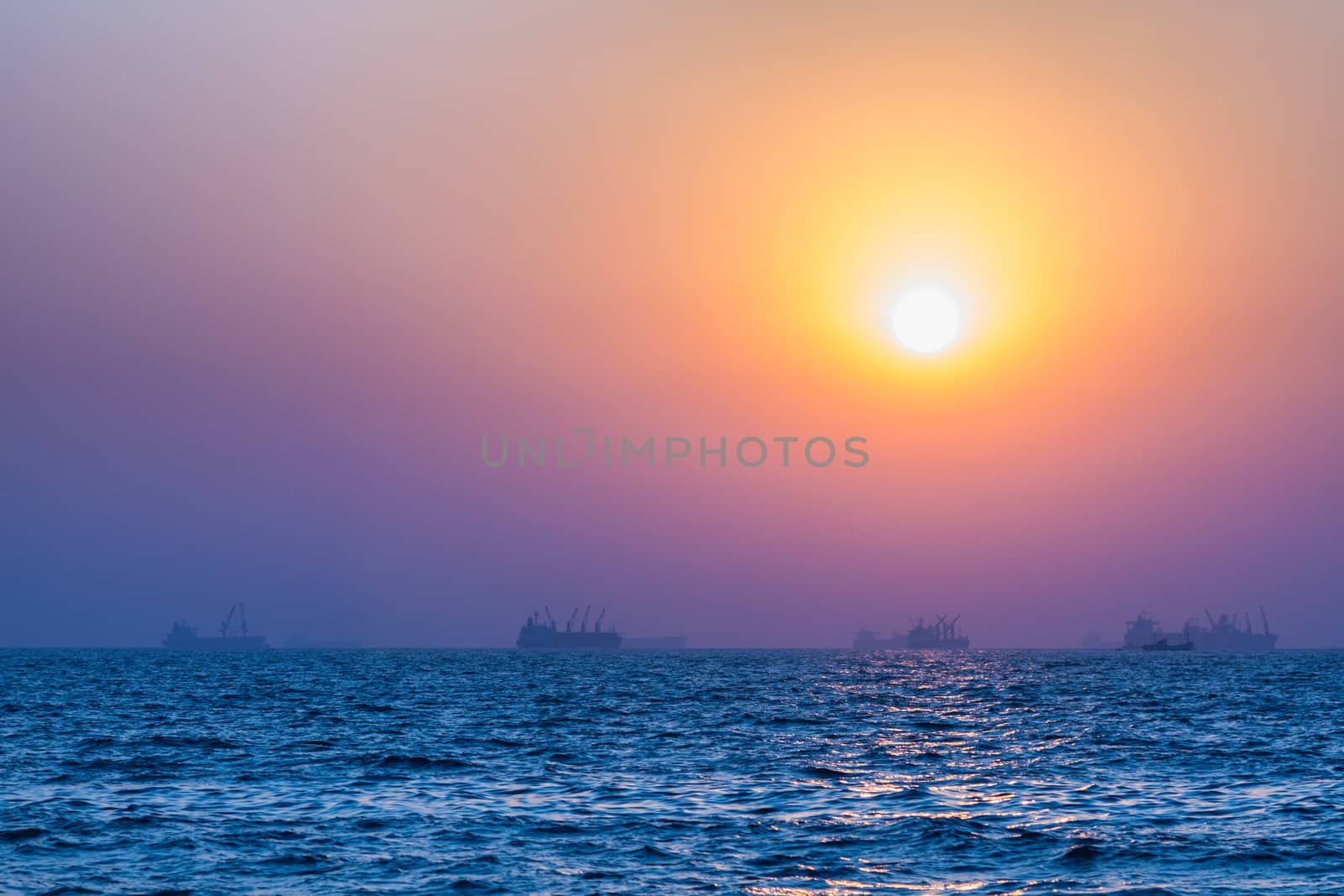 Scenic view of beautiful sunset above the Arabian sea. Cargo ship on the background