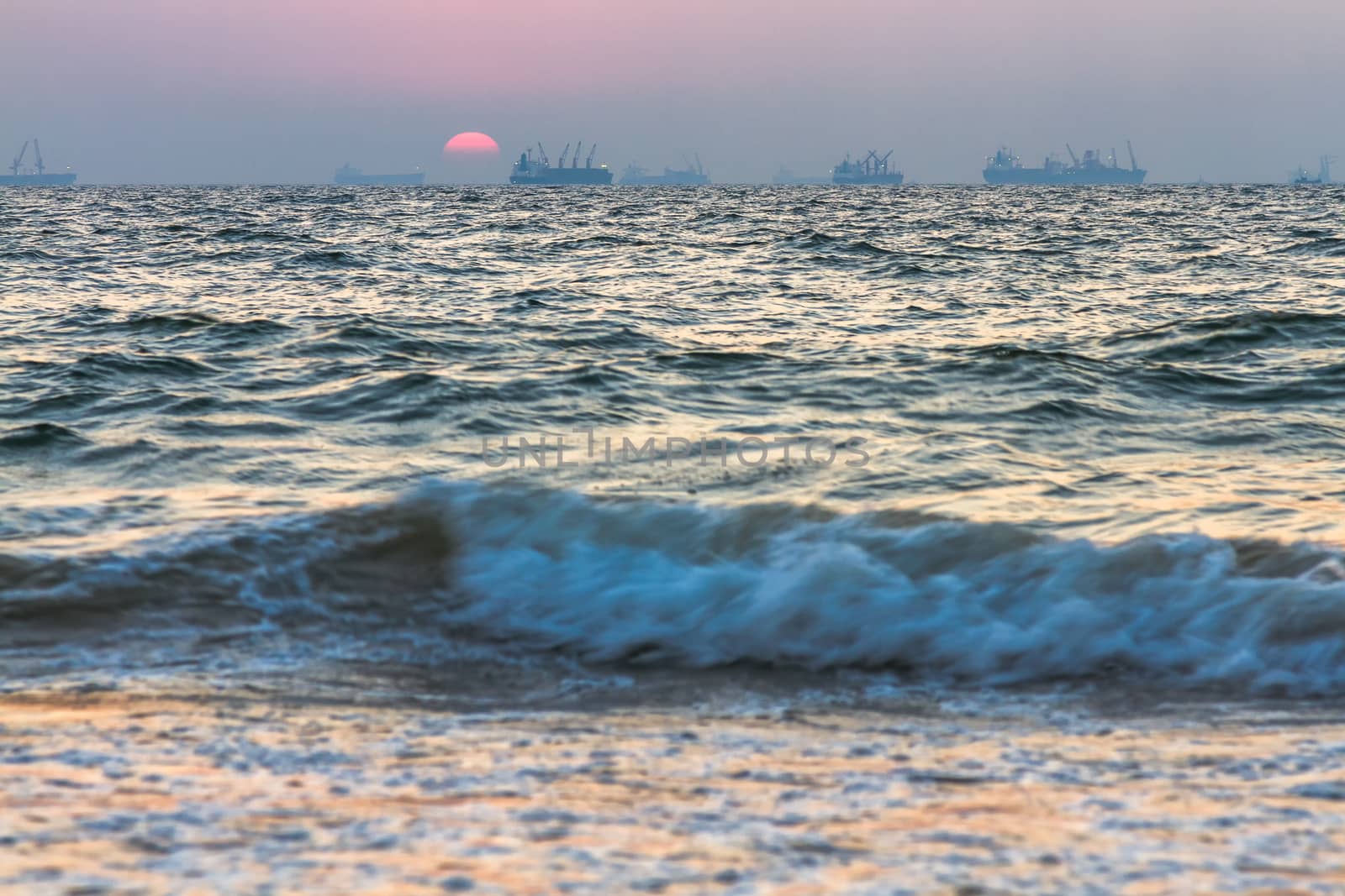 Scenic view of beautiful sunset above the Arabian sea. Cargo ship on the background