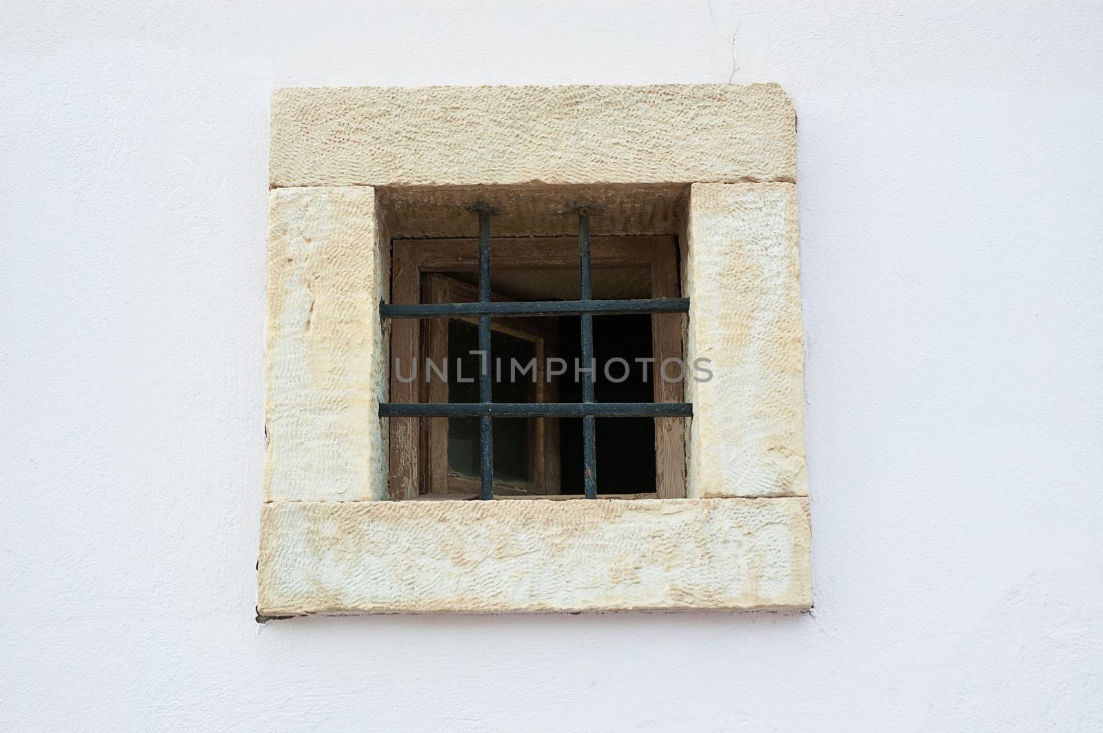 Old open window on white shabby wall with bars