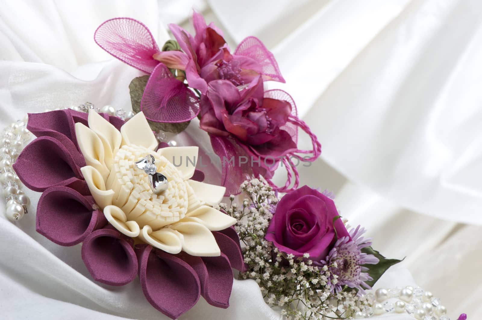 flowers and wedding rings on white background