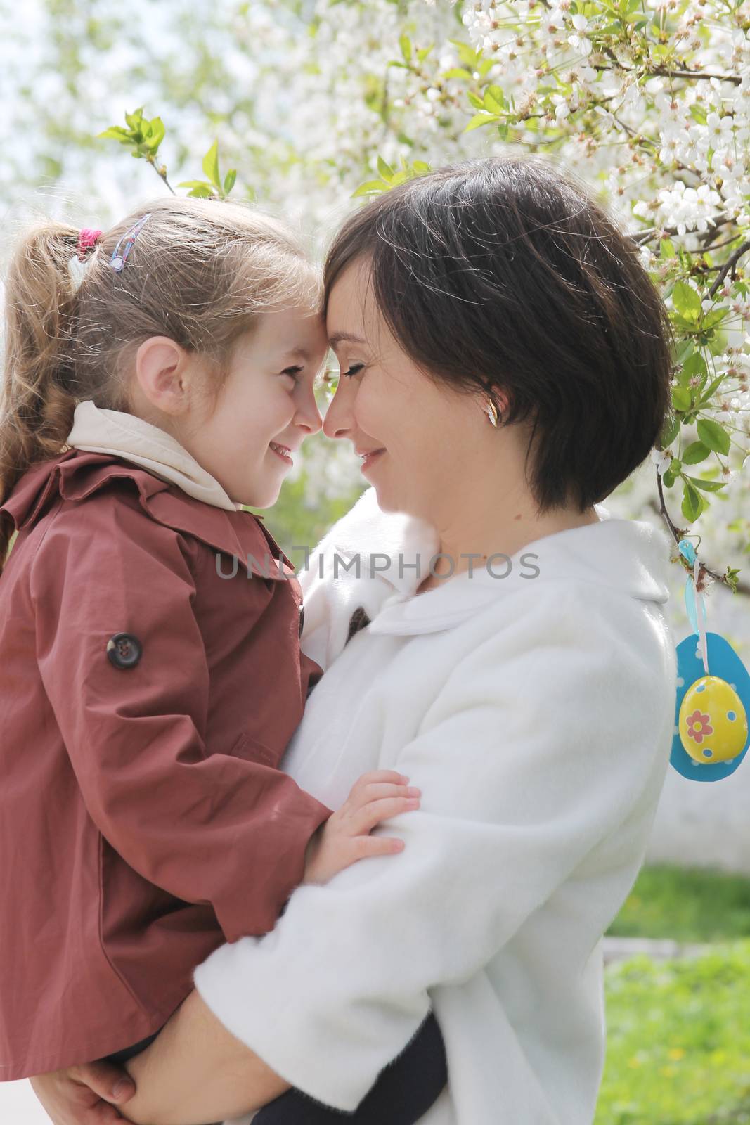 Happy mother and baby girl hugging among spring garden