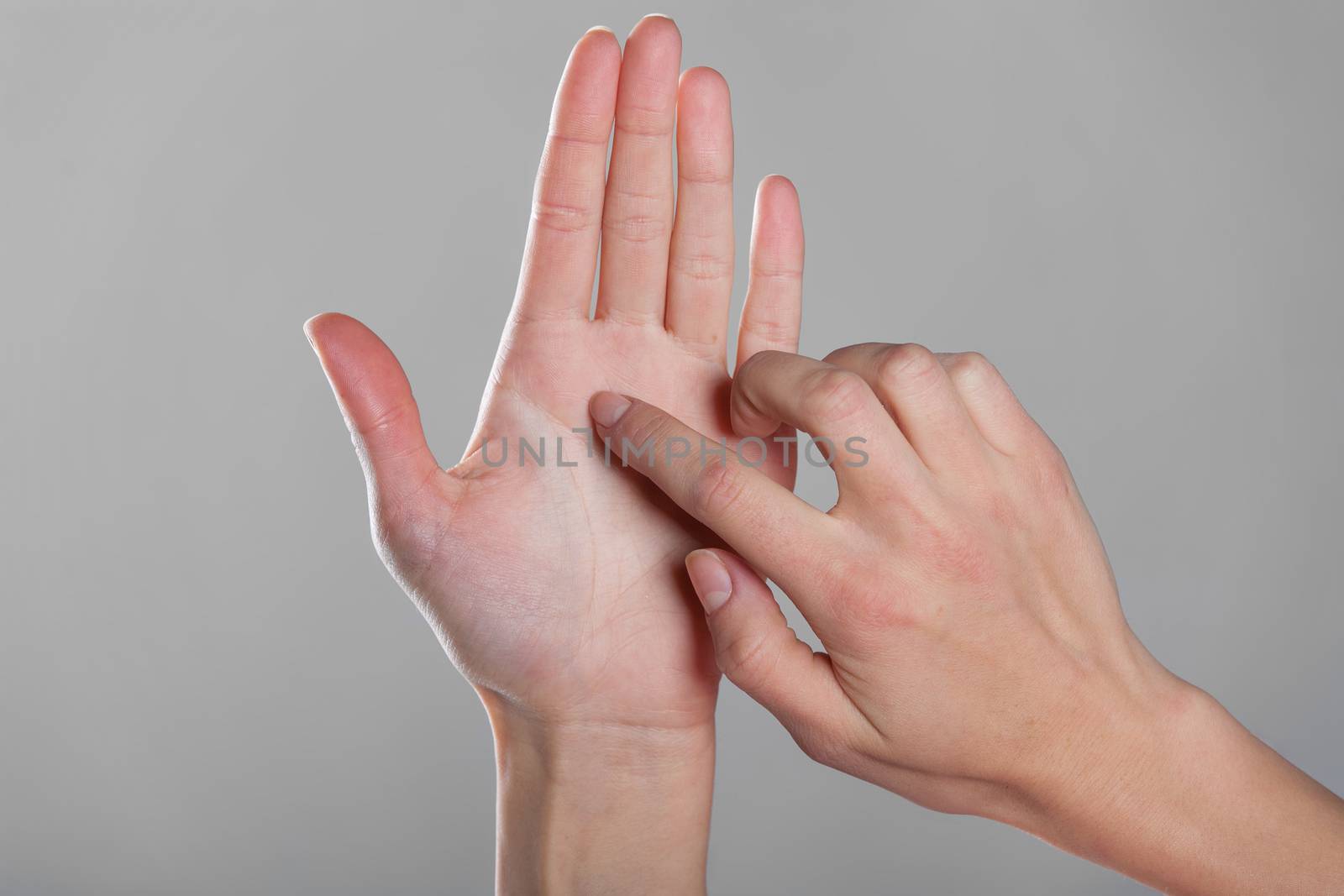 Female finger touches an open hand on gray background.