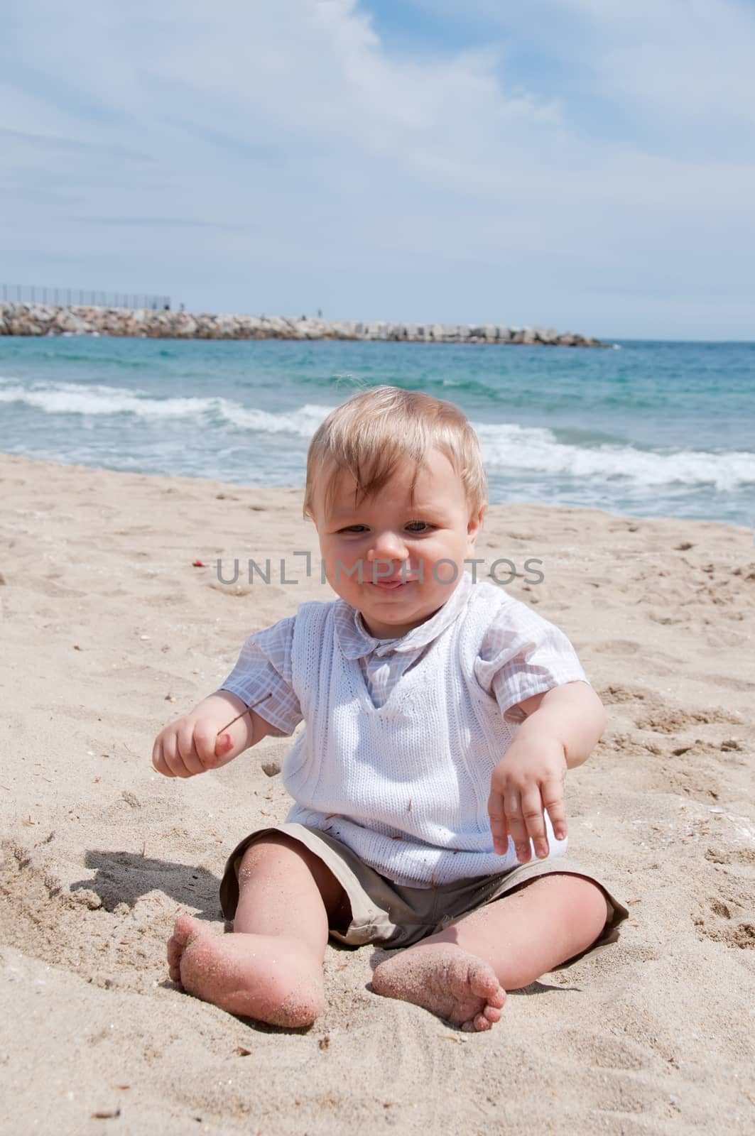 Happy little boy sitting on the beach