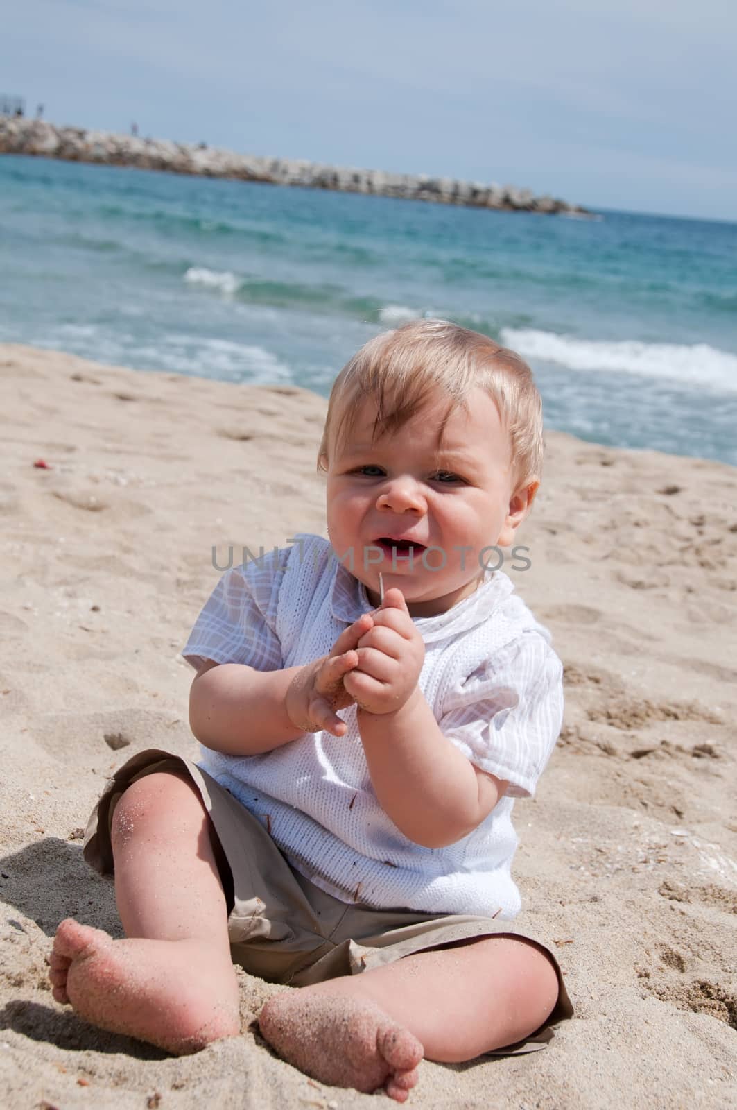 Happy cute boy sitting on the beach by anytka