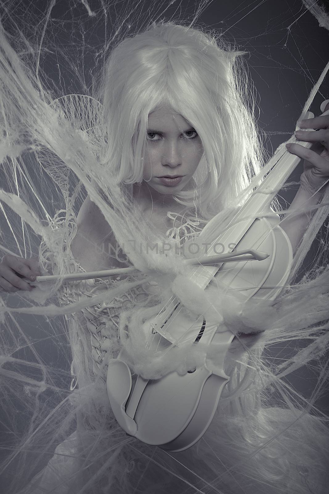 Sensuality beautiful woman trapped in a spider web with a white violin, lace dress