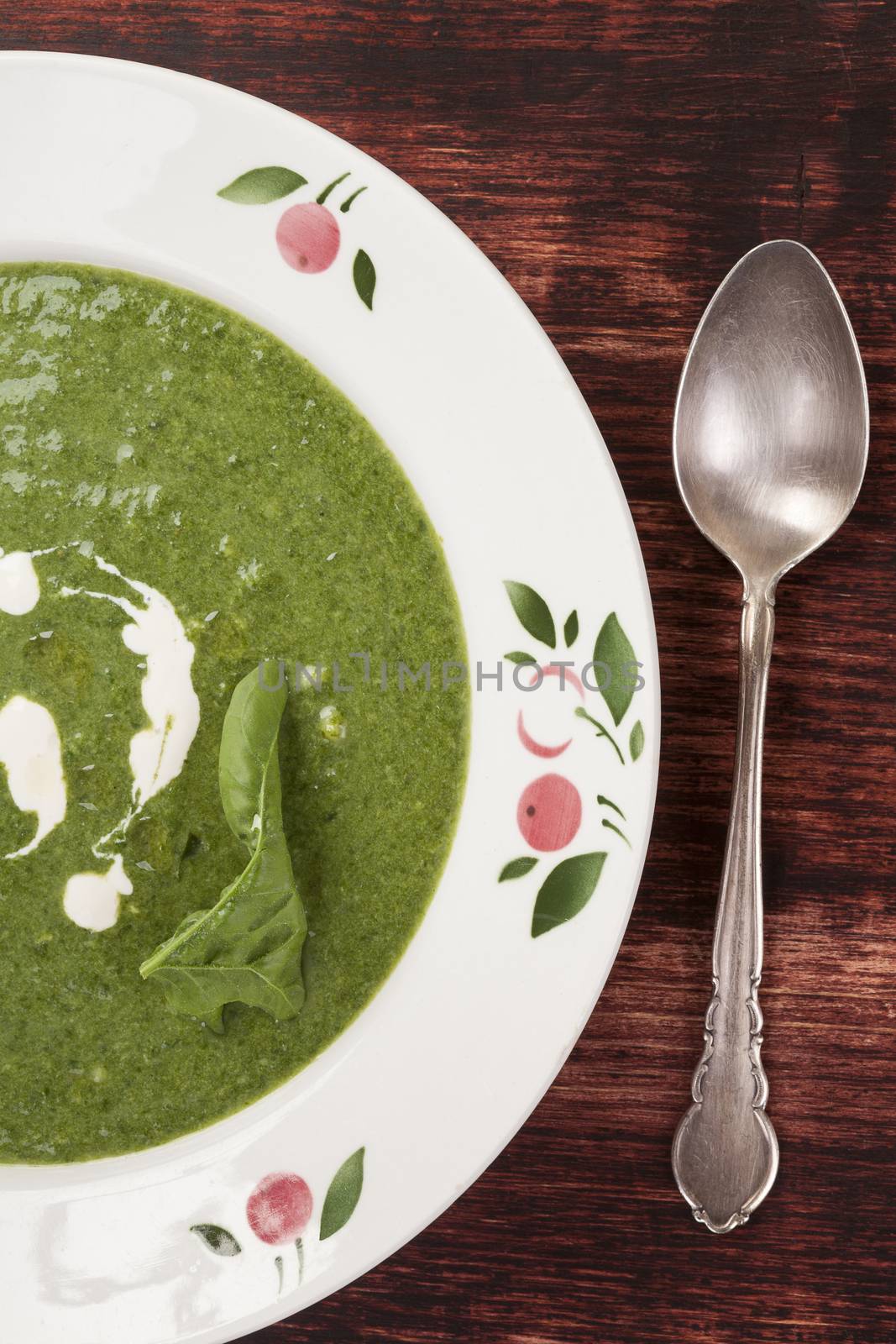 Spinach cream soup on wooden background with silver spoon, top view. Rustic, country style traditional eating. 