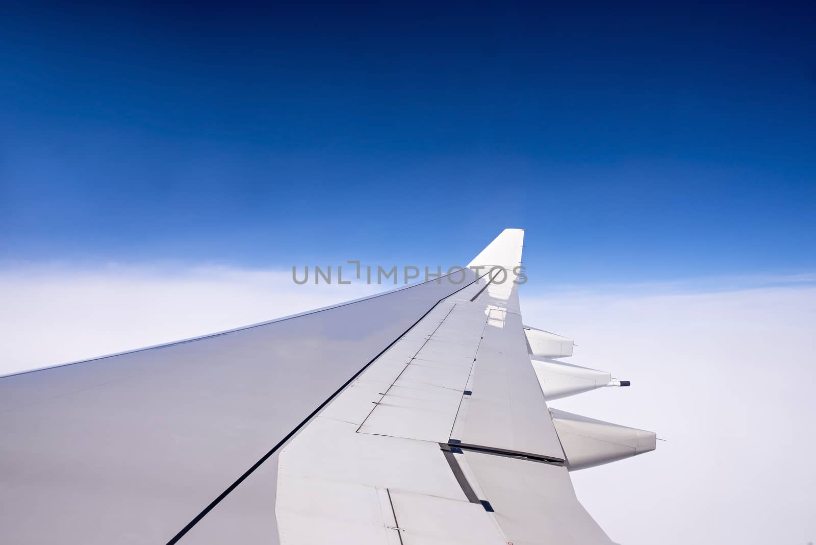 Wing of an airplane flying above the clouds