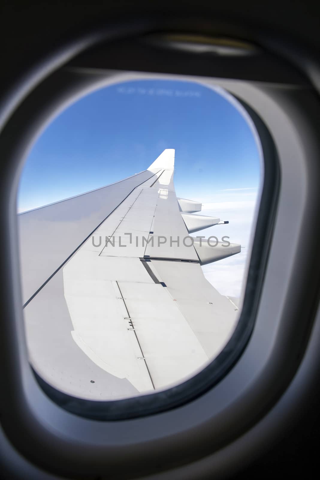 Wing of an airplane flying above the clouds by Yuri2012