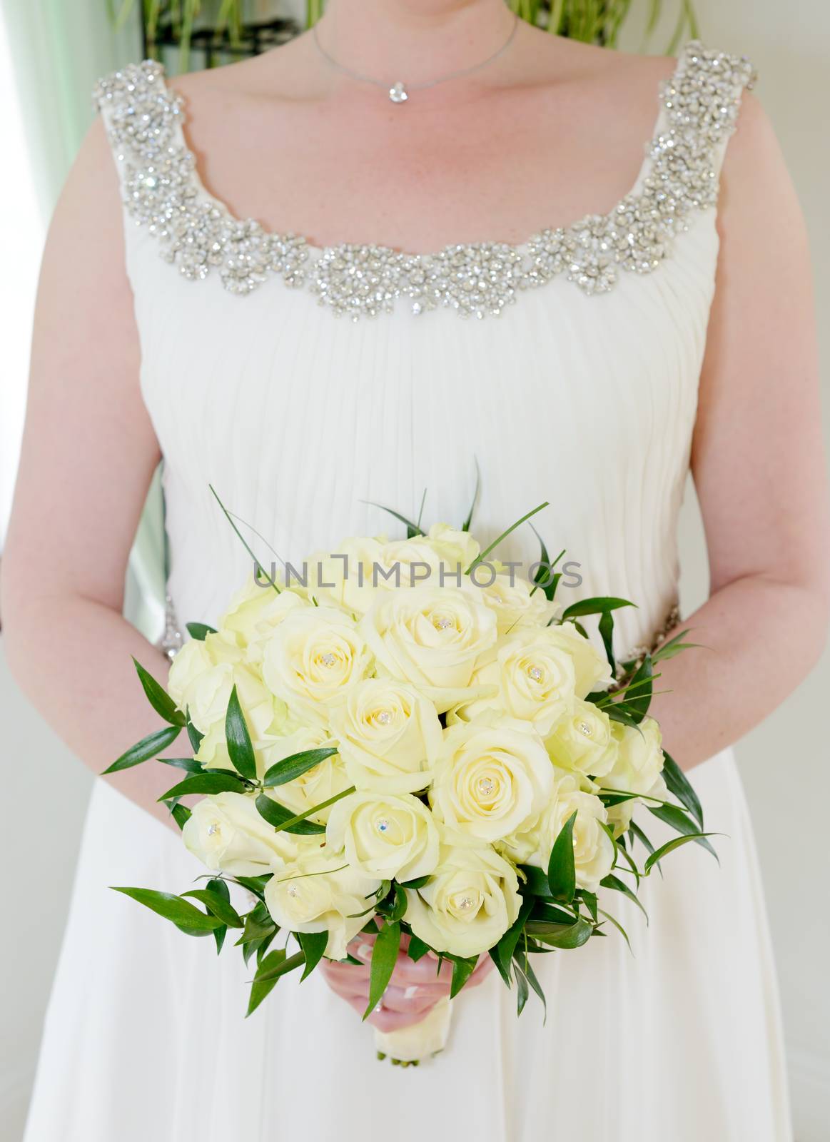 Closeup of bride holding flower arrangement with yellow roses