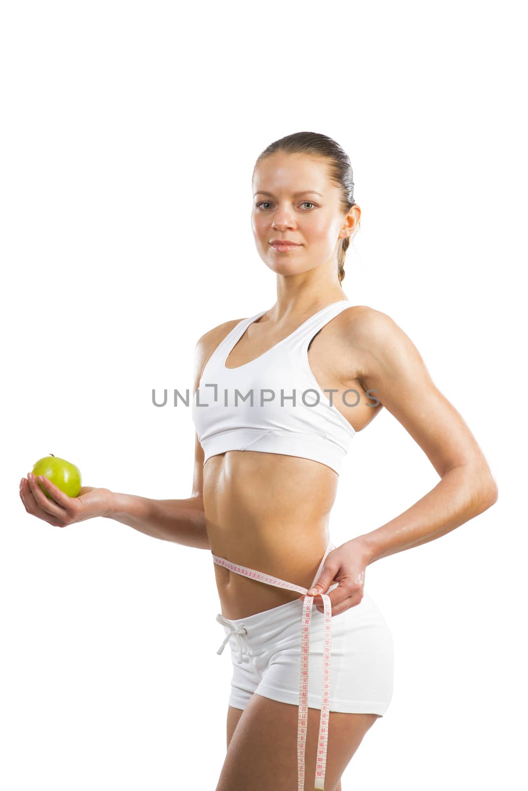 young athletic girl measuring waist measuring tape and holding a green apple, concept of healthy eating, isolated on white background